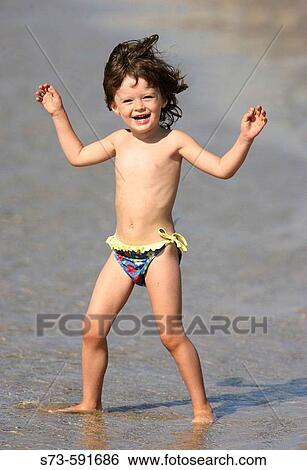 Stock Photograph - 3 year old girl on the beach. Fotosearch