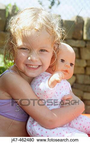 3 year old girl outside in swimming costume holding a doll smiling into camera View Large Photo Image Stock Image - 3 year old girl outside in swimming costume holding a doll smiling into camera. Fotosearch