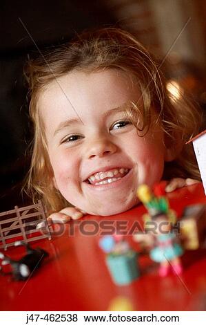 3 year old girl resting her chin on the red table smiling very cheekily into camera View Large Photo Image Stock Photo - 3 year old girl resting her chin on the red table smiling very cheekily into camera. Fotosearch