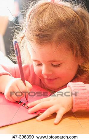 Stock Image - 3 year old girl sitting at a table drawing. Fotosearch