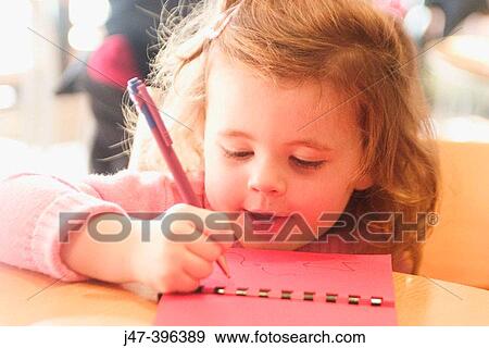 Stock Photo - 3 year old girl sitting at a table drawing. Fotosearch