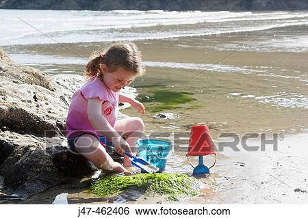 3 year old girl sitting by a rock pool at the beach digging, smiling. South Beach, Salcolmbe, England View Large Photo Image Stock Photograph - 3 year old girl sitting by a rock pool at the beach digging, smiling. South Beach, Salcolmbe, England. Fotosearch