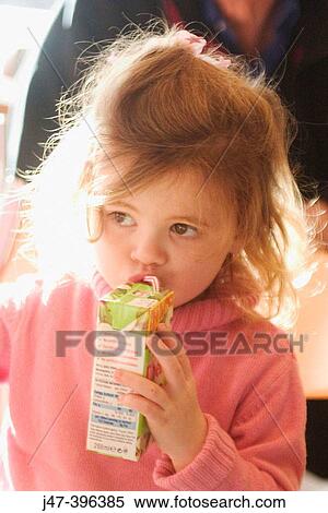 Stock Photography - 3 year old girl sitting in a cake drinking juice through straw. Fotosearch