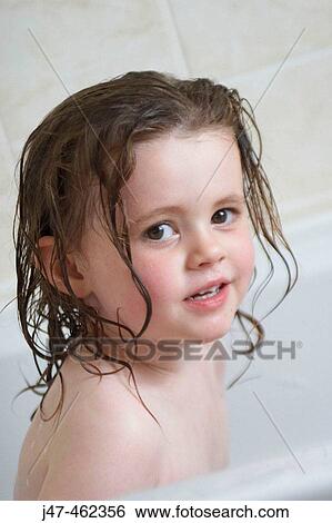 Stock Photograph - 3 year old girl sitting in the bath smiling into camera. Fotosearch