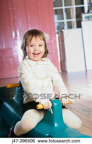 3 year old girl sitting on a seesaw, smiling into camera View Large Photo Image Stock Photograph - 3 year old girl sitting on a seesaw, smiling into camera. Fotosearch