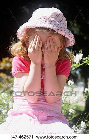 3 year old girl sitting on a wall outside, covering her eyes with her hands View Large Photo Image Stock Image - 3 year old girl sitting on a wall outside, covering her eyes with her hands. Fotosearch