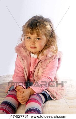 Stock Image - 3 year old girl sitting smiling into camera. Fotosearch