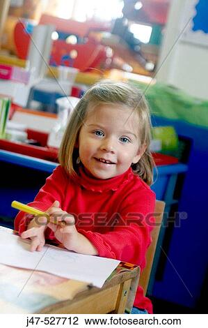 Stock Image - 3 year old girl smiling into camera at nursery. Fotosearch