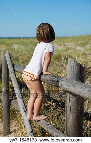 3 year old girl standing on a fence and watching dunes by the Baltic Sea, Poland View Large Photo Image Stock Image - 3 year old girl standing on a fence and watching dunes by the Baltic Sea, Poland. Fotosearch