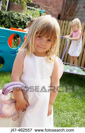 Stock Photo - 3 year old girl standing outside in the garden. Fotosearch