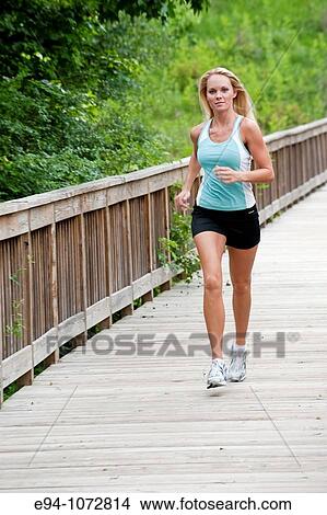 Picture - 30 year old blonde woman jogging in work out clothes. Fotosearch