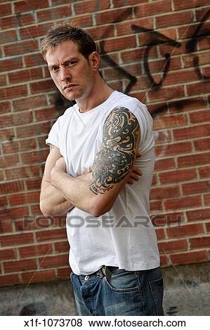 30 year old man standing alone with heavily tattooed arms View Large Photo Image Stock Photo - 30 year old man standing alone with heavily tattooed arms. Fotosearch
