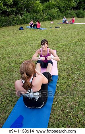 30 year old woman in work out clothing leading a boot camp doing sit ups with a partners View Large Photo Image Picture - 30 year old woman in work out clothing leading a boot camp doing sit ups with a partners. Fotosearch