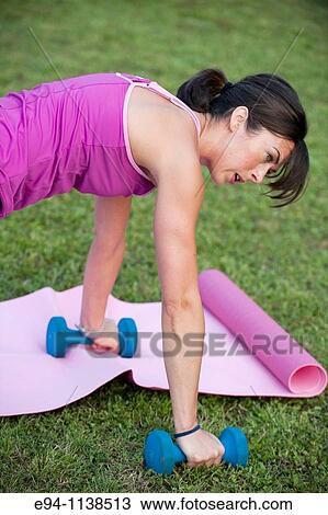 30 year old woman in work out clothing leading a boot camp demonstrating push ups with hands on dumbbells View Large Photo Image Stock Image - 30 year old woman in work out clothing leading a boot camp demonstrating push ups with hands on dumbbells. Fotosearch