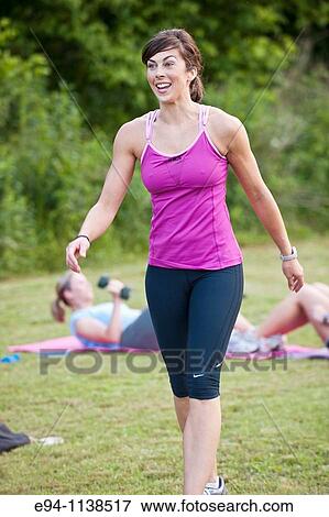 30 year old woman in work out clothing leading a boot camp with women in background doing sit ups View Large Photo Image Stock Photo - 30 year old woman in work out clothing leading a boot camp with women in background doing sit ups. Fotosearch