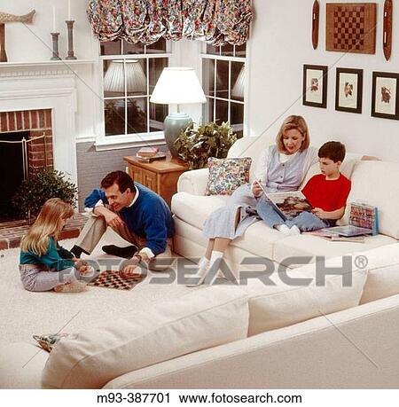 30s Parents With Son And Daughter In Well Lit Living Room