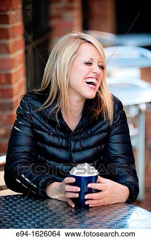 31 year old blond woman sitting in an outdoor cafe with a mug of coffee laughing looking away from the camera View Large Photo Image Picture - 31 year old blond woman sitting in an outdoor cafe with a mug of coffee laughing looking away from the camera. Fotosearch