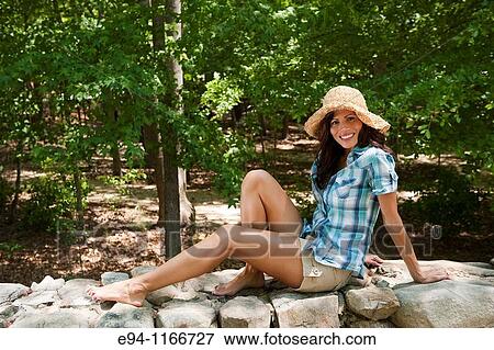 32 year old brunette woman in casual summer dress sitting on a stone wall smiling at the camera. View Large Photo Image Stock Photo - 32 year old brunette woman in casual summer dress sitting on a stone wall smiling at the camera.. Fotosearch