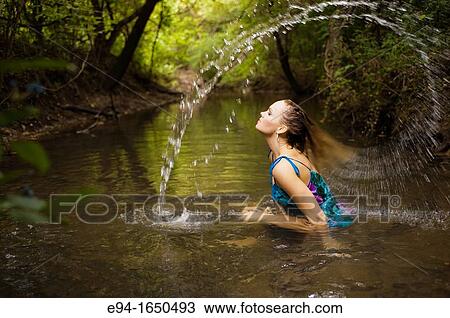 34 year old blond woman in a flower print dress sitting in the water of a small creek swooshing her hair in a water arc over her head View Large Photo Image Stock Image - 34 year old blond woman in a flower print dress sitting in the water of a small creek swooshing her hair in a water arc over her head. Fotosearch