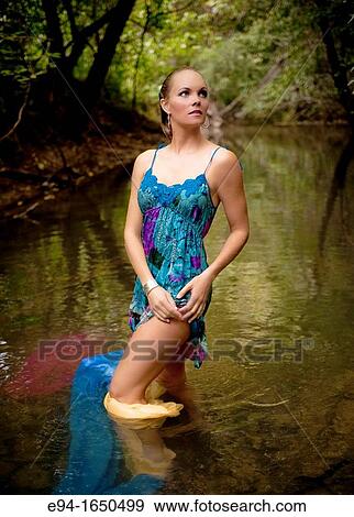 34 year old blond woman in a short flower print dress standing in a small creek looking away from the camera View Large Photo Image Stock Photo - 34 year old blond woman in a short flower print dress standing in a small creek looking away from the camera. Fotosearch