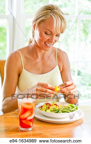 35 year old blond woman sitting at a kitchen table with a salad and a glass of iced tea, selective focus View Large Photo Image Stock Photo - 35 year old blond woman sitting at a kitchen table with a salad and a glass of iced tea, selective focus. Fotosearch