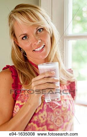 35 year old blond woman standing in a kitchen holding cold fruit drink View Large Photo Image Stock Photo - 35 year old blond woman standing in a kitchen holding cold fruit drink. Fotosearch