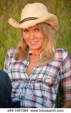 35 year old blond woman wearing jeans and a straw hat sitting on grass smiling at camera. View Large Photo Image Picture - 35 year old blond woman wearing jeans and a straw hat sitting on grass smiling at camera.. Fotosearch