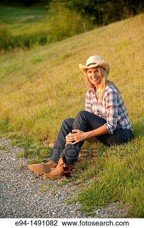 35 year old blond woman wearing jeans and a straw hat sitting on grass near a country road. View Large Photo Image Stock Image - 35 year old blond woman wearing jeans and a straw hat sitting on grass near a country road.. Fotosearch