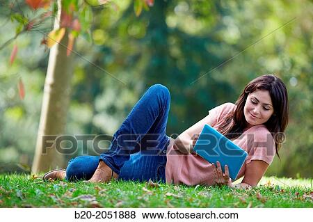 Stock Photo - 35 year old woman with digital tablet in park. Donostia. San Sebastian. Gipuzkoa. Basque Country, Spain.. Fotosearch