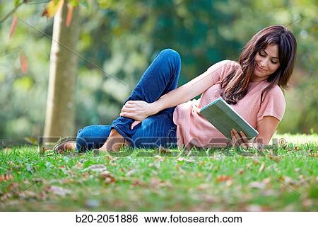Stock Photograph - 35 year old woman with digital tablet in park. Donostia. San Sebastian. Gipuzkoa. Basque Country, Spain.. Fotosearch