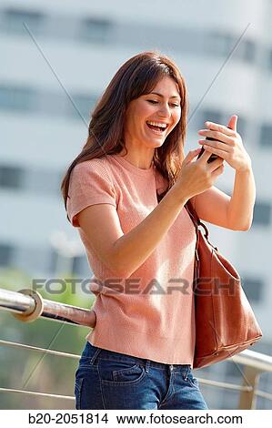 Picture - 35 year old woman with smartphone in town. Donostia. San Sebastian. Gipuzkoa. Basque Country, Spain.. Fotosearch