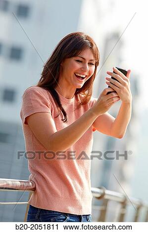 Stock Image - 35 year old woman with smartphone in town. Donostia. San Sebastian. Gipuzkoa. Basque Country, Spain.. Fotosearch