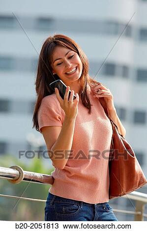 Stock Image - 35 year old woman with smartphone in town. Donostia. San Sebastian. Gipuzkoa. Basque Country, Spain.. Fotosearch