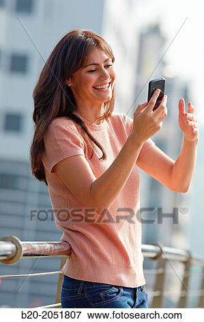 Stock Photo - 35 year old woman with smartphone in town. Donostia. San Sebastian. Gipuzkoa. Basque Country, Spain.. Fotosearch