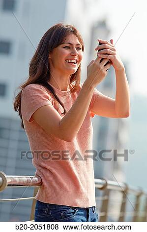 Stock Photo - 35 year old woman with smartphone in town. Donostia. San Sebastian. Gipuzkoa. Basque Country, Spain.. Fotosearch