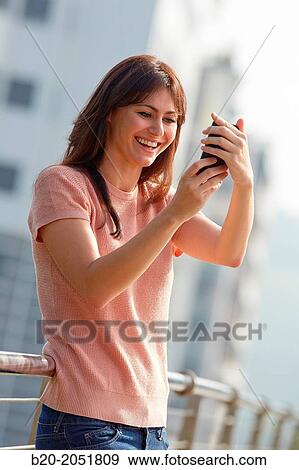 Stock Photo - 35 year old woman with smartphone in town. Donostia. San Sebastian. Gipuzkoa. Basque Country, Spain.. Fotosearch