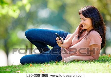Stock Photo - 35 year old woman with smartphone in park. Donostia. San Sebastian. Gipuzkoa. Basque Country, Spain.. Fotosearch
