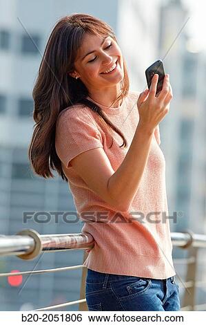 Stock Photograph - 35 year old woman with smartphone in town. Donostia. San Sebastian. Gipuzkoa. Basque Country, Spain.. Fotosearch