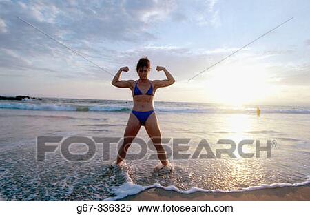 Stock Photography - 35 years old woman flexes muscles on the beach. Santa Monica. California. USA.. Fotosearch