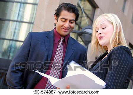 35 yr old ethnic business man standing with 25 yr old caucasian business woman discussing file information View Large Photo Image Stock Photo - 35 yr old ethnic business man standing with 25 yr old caucasian business woman discussing file information. Fotosearch