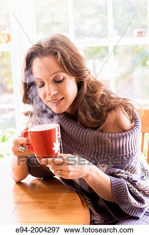 37 year old brunette woman wearing a big sweater and holding a cup of steaming tea in a kitchen setting. View Large Photo Image Stock Photo - 37 year old brunette woman wearing a big sweater and holding a cup of steaming tea in a kitchen setting.. Fotosearch