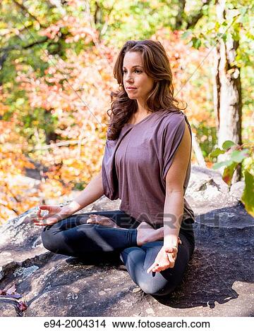 37 year old brunette woman wearing fitness clothes doing a yoga pose in a forest setting. View Large Photo Image Picture - 37 year old brunette woman wearing fitness clothes doing a yoga pose in a forest setting.. Fotosearch