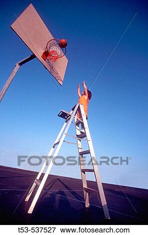 Stock Photo - 4 1/2 year old child budge shoots a hoop with the help of a ladder.. Fotosearch