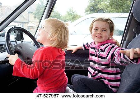 4 and 2 year old girls pretending to drive the car View Large Photo Image Stock Photo - 4 and 2 year old girls pretending to drive the car. Fotosearch