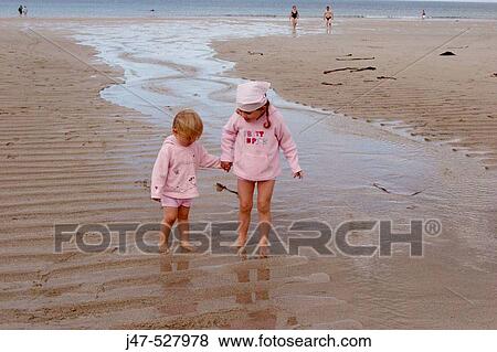 4 and 2 year old girls standing on the beach holding hands, laughing View Large Photo Image Stock Photo - 4 and 2 year old girls standing on the beach holding hands, laughing. Fotosearch