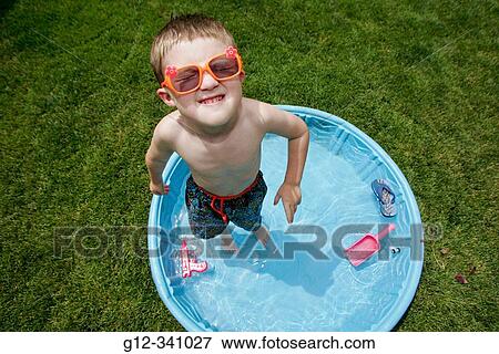 Stock Photo - 4 year old boy playing in backyard pool. Fotosearch