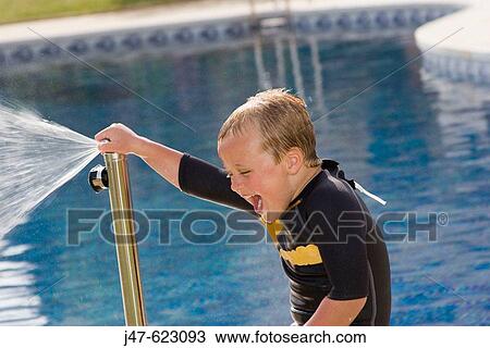 4 year old boy, standing next a swimming pool, holding a tap, squirting with water, laughing View Large Photo Image Stock Image - 4 year old boy, standing next a swimming pool, holding a tap, squirting with water, laughing. Fotosearch