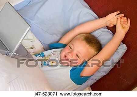 4 year old boy watching a portable dvd player in bed, smiling, stretching his arms over his head View Large Photo Image Stock Image - 4 year old boy watching a portable dvd player in bed, smiling, stretching his arms over his head. Fotosearch