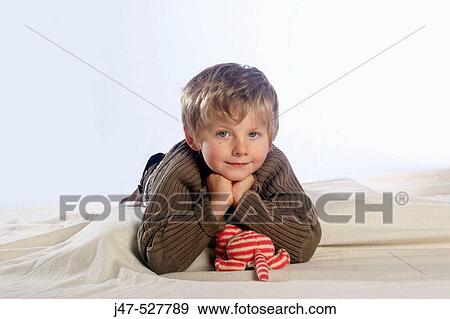 4 year old boyl with blonde hair, smiling into camera, in the studio, lying on the floor, hands under his chin View Large Photo Image Stock Photo - 4 year old boyl with blonde hair, smiling into camera, in the studio, lying on the floor, hands under his chin. Fotosearch
