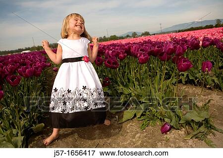 Stock Photo - 4 year old girl in black and white dress playing and smiling in a tulip fields in Skagit Valley, Washington, USA. Fotosearch